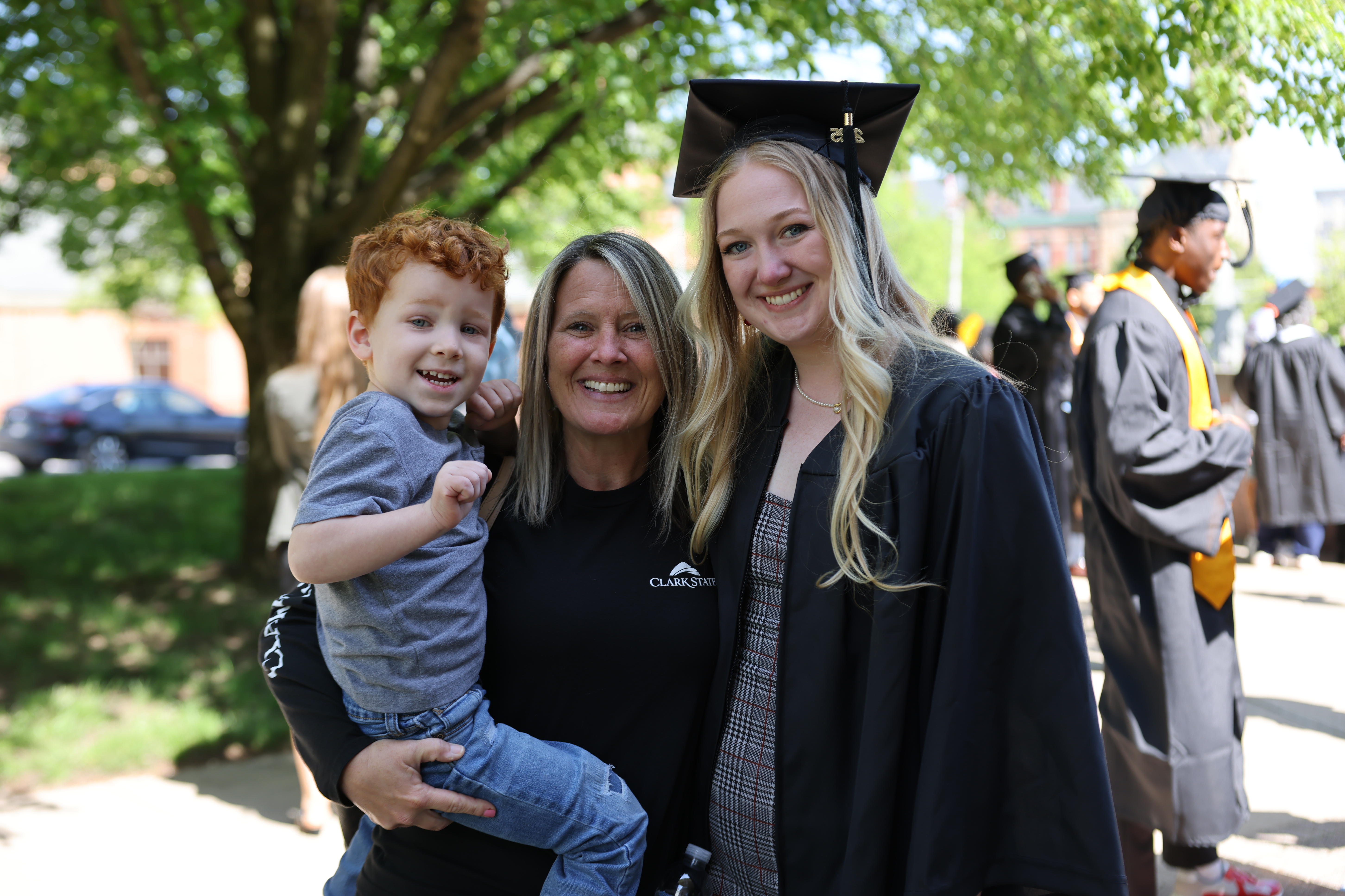 Student after graduation in cap and gown with family
